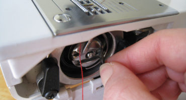 Com inserir un fil, una doble agulla i una bobina en una màquina de cosir?
